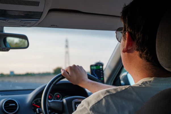 A man wearing a white t-shirt and sunglasses while driving a car